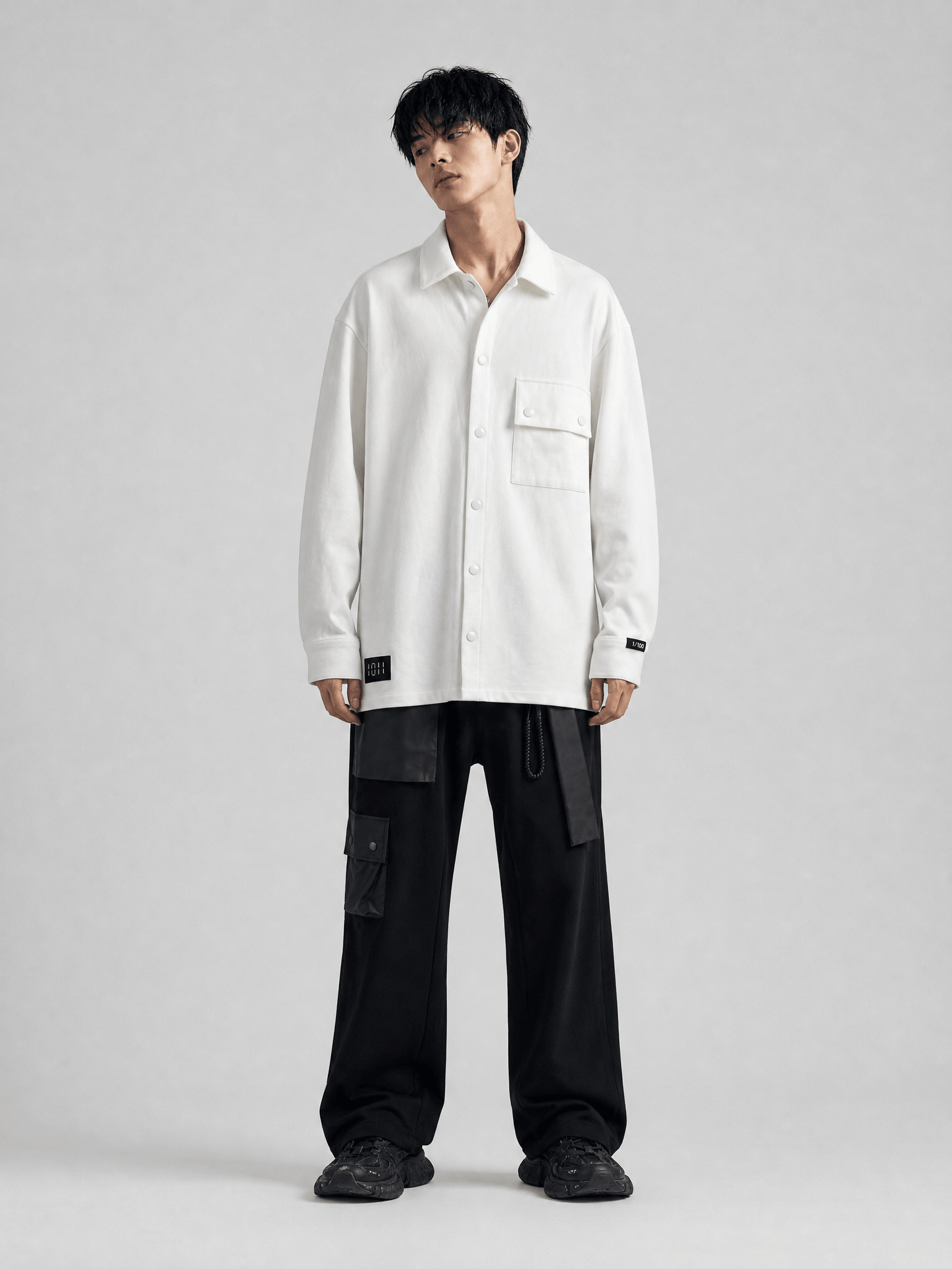Person wearing a white shirt and black pants on a gray background