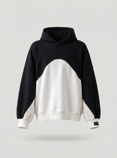A color-blocked pullover hoodie with a black upper body and hood, and a large white lower body and sleeves, shown against a light gray background.