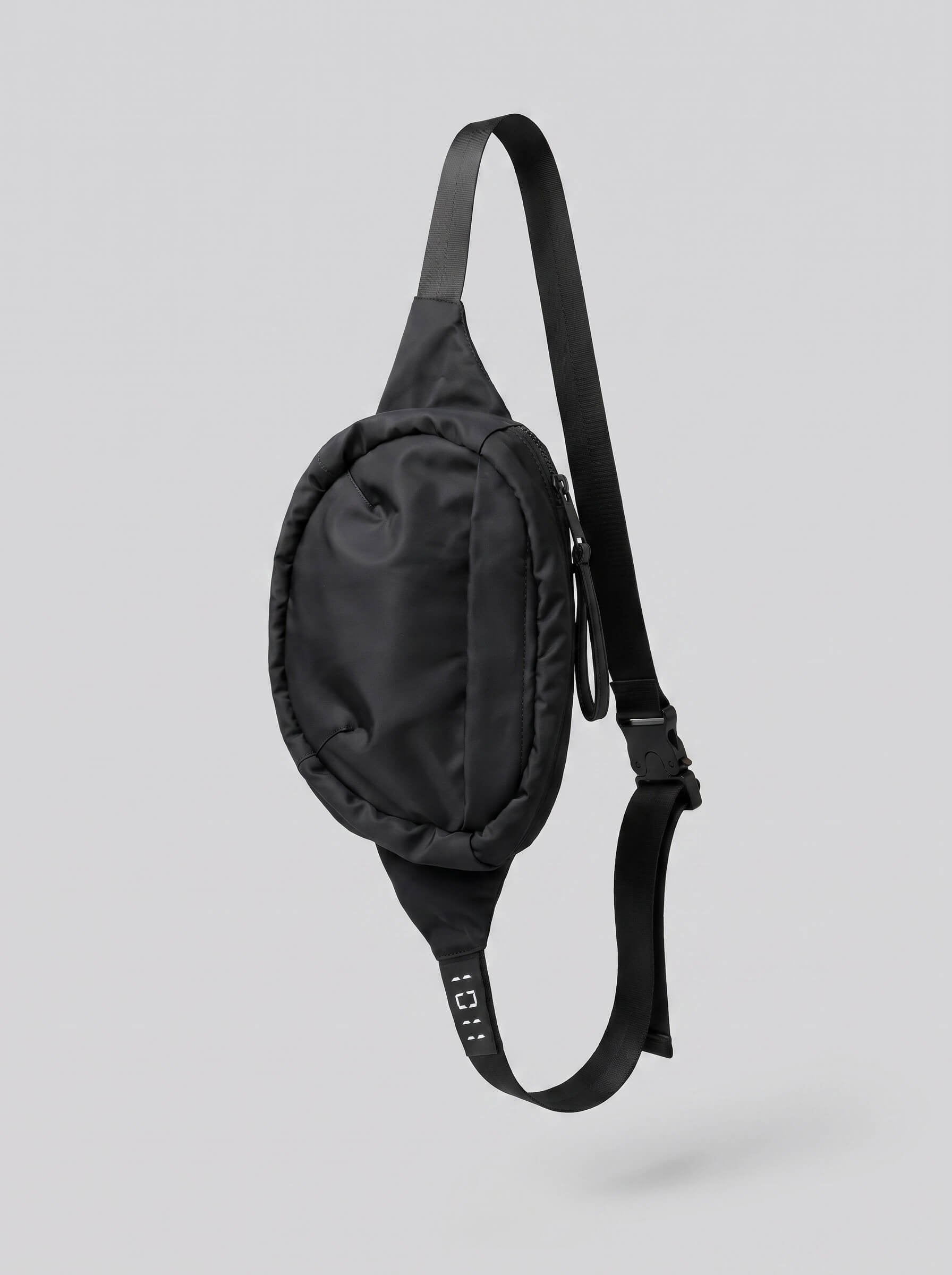 Black waist bag with a strap on a light gray background
