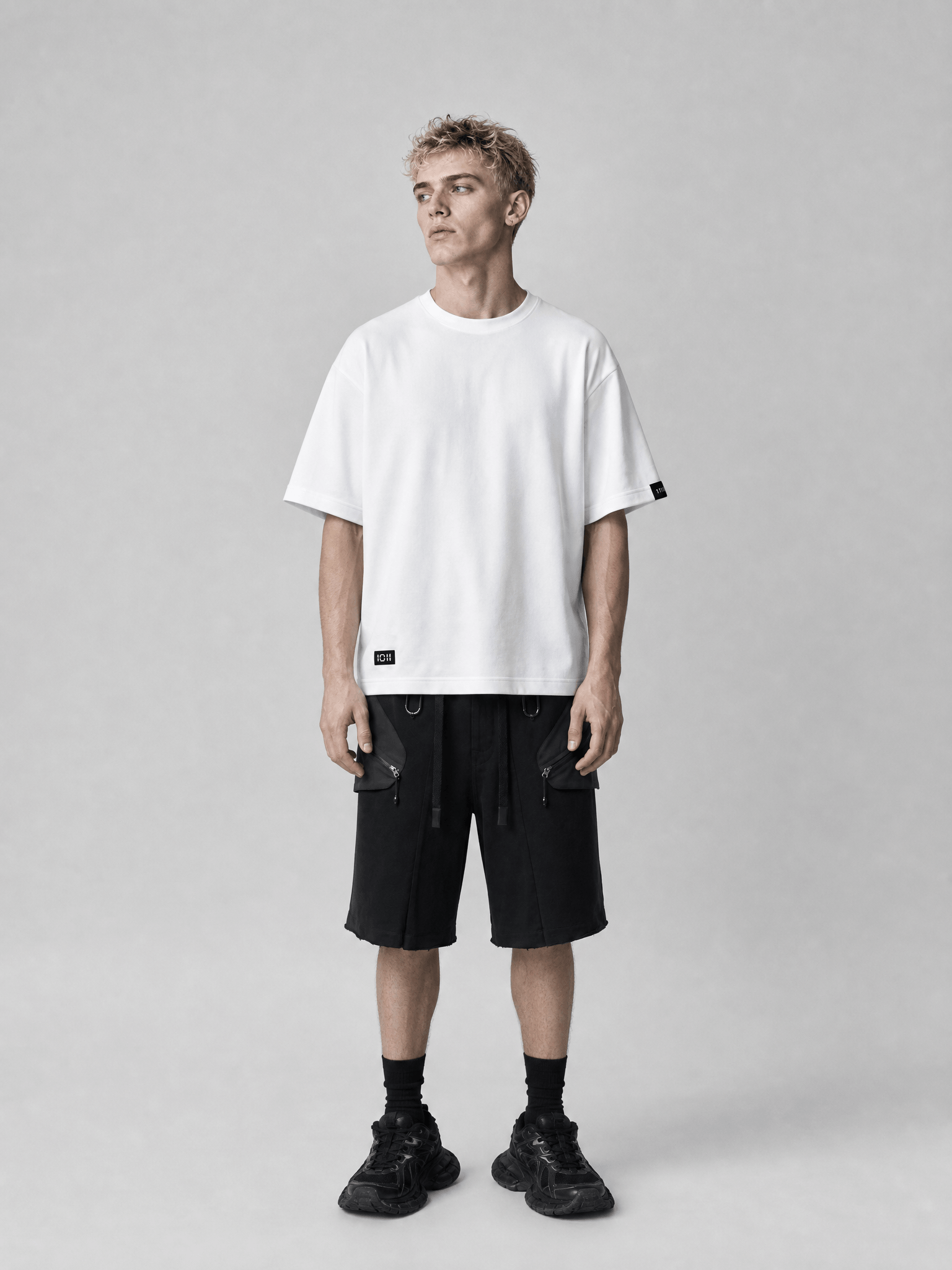 Person wearing a white t-shirt and black shorts on a gray background