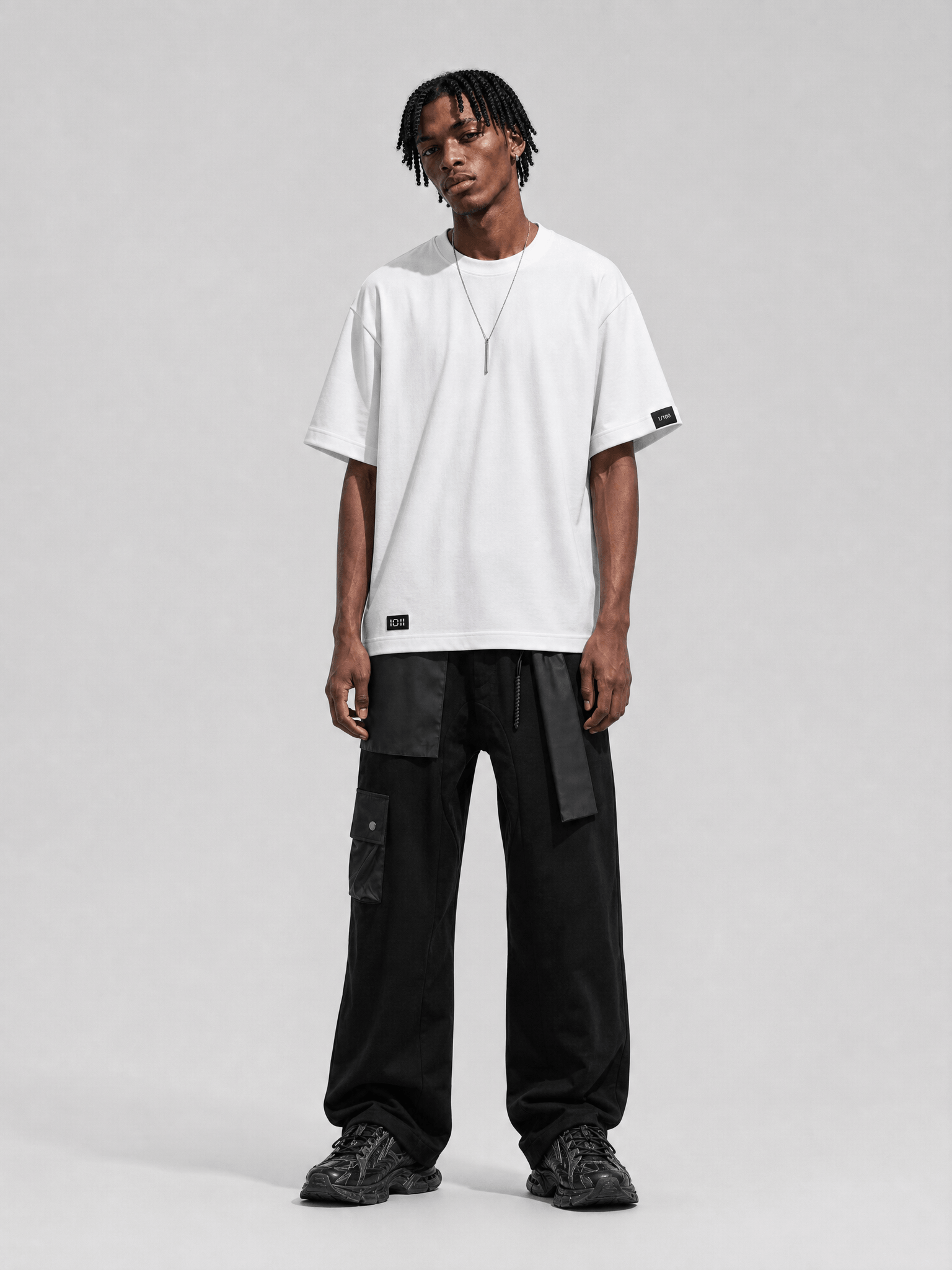 Person wearing a white t-shirt and black pants on a gray background