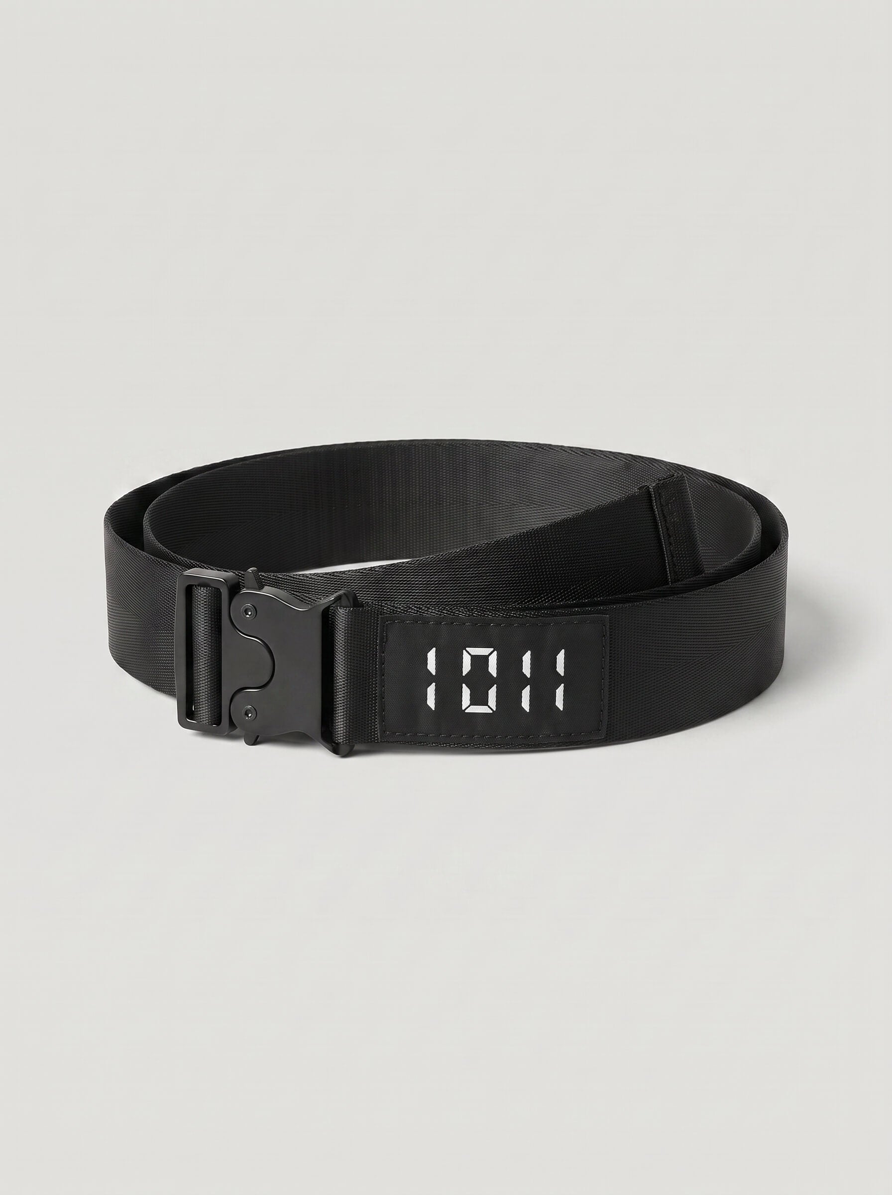 A black web belt with a digital LED-style buckle displaying '10:11' in white, coiled on a light gray background.